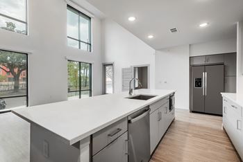 a kitchen with white countertops and a large white island with a stainless steel sink